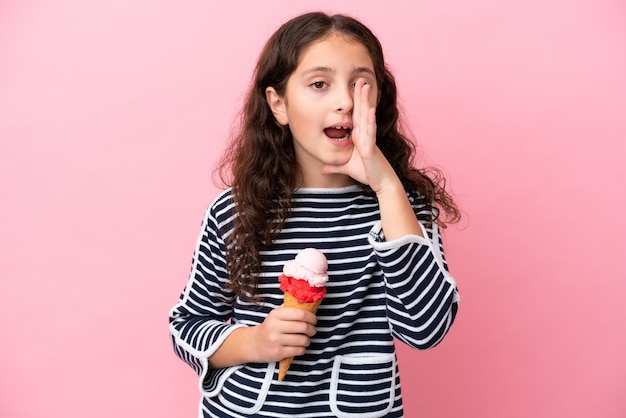 Little caucasian girl holding an ice cream isolated on pink background shouting with mouth wide open