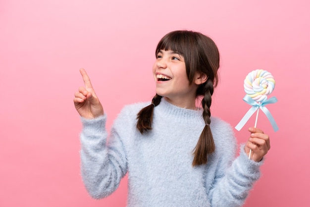 Little caucasian girl holding a lollipop pointing up a great idea