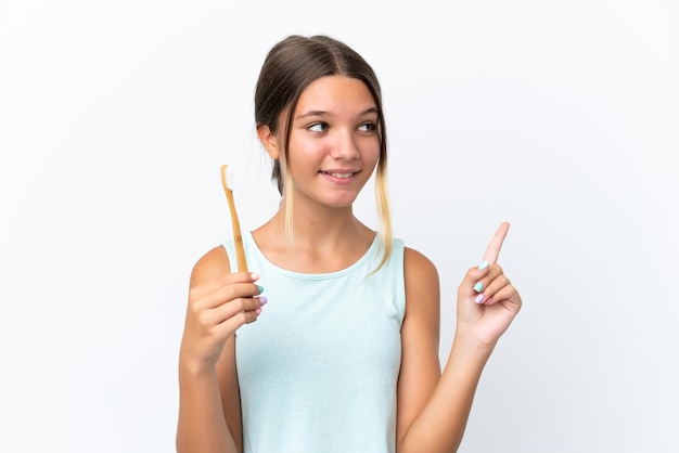 Little caucasian girl holding a toothbrush isolated on white background intending to realizes the solution while lifting a finger up