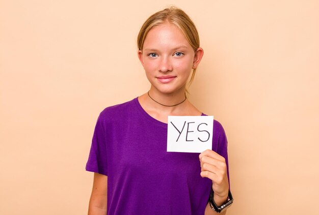 Little caucasian girl holding yes placard isolated on beige background