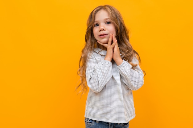 little caucasian girl is embrassed on yellow wall