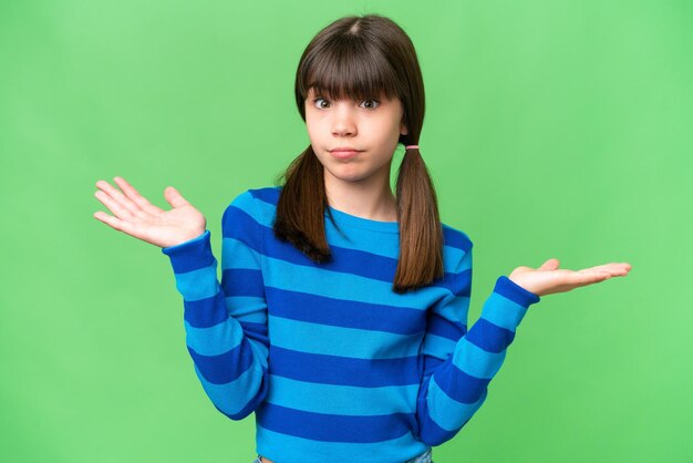 Little caucasian girl over isolated background having doubts while raising hands