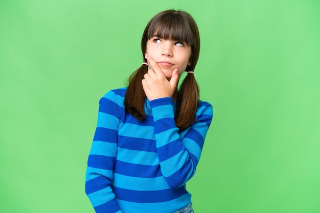 Photo little caucasian girl over isolated background having doubts