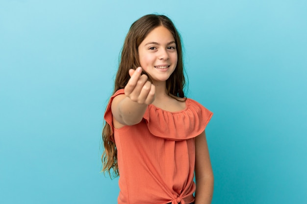 Little caucasian girl isolated on blue background making money gesture