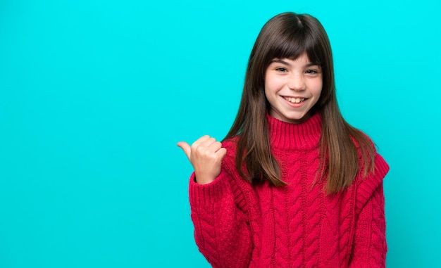 Little caucasian girl isolated on blue background pointing to the side to present a product