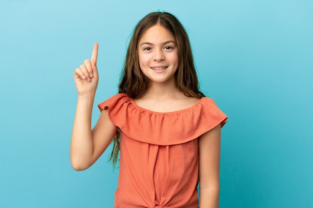 Little caucasian girl isolated on blue background pointing up a great idea