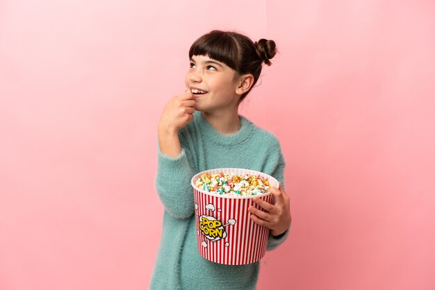 Little caucasian girl isolated holding a big bucket of popcorns