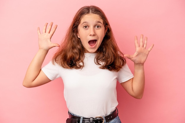 Little caucasian girl isolated on pink background receiving a pleasant surprise, excited and raising hands.