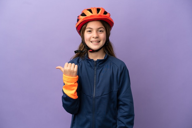 Little caucasian girl isolated on purple background pointing to the side to present a product