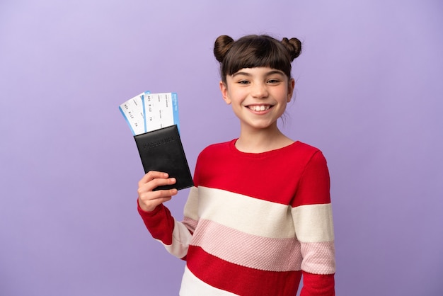 Маленькая кавказская девушка изолирована на фиолетовом, счастлива в отпуске с паспортом и билетами на самолет