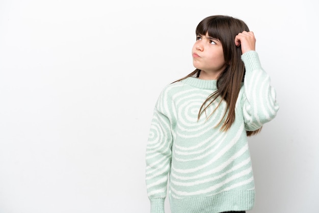 Little caucasian girl isolated on white background having doubts while scratching head