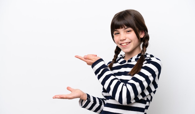 Little caucasian girl isolated on white background holding copyspace imaginary on the palm to insert an ad