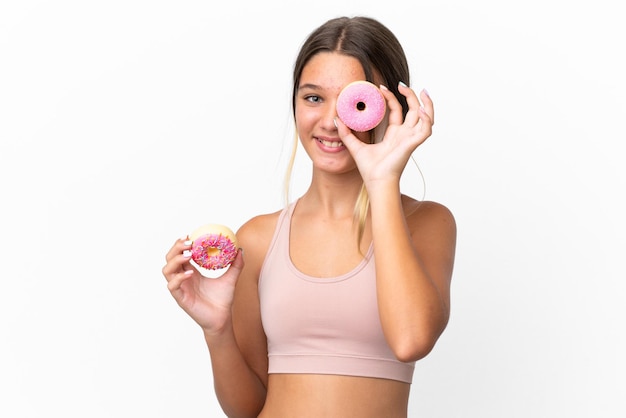 Little caucasian girl isolated on white background holding a donut and happy