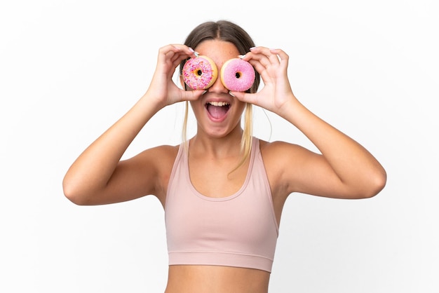 Little caucasian girl isolated on white background holding donuts in an eye