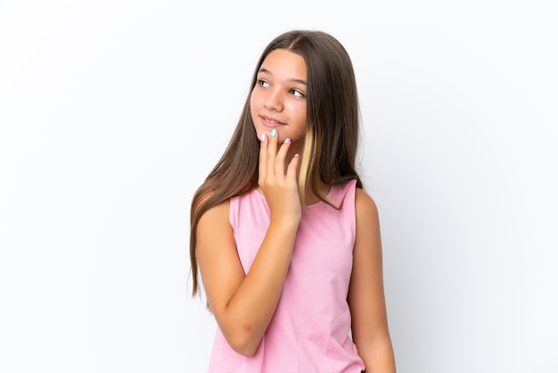 Little caucasian girl isolated on white background looking up while smiling