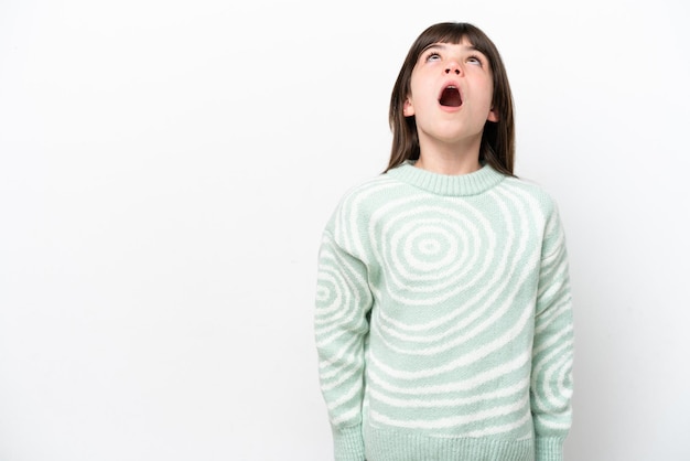 Little caucasian girl isolated on white background looking up and with surprised expression