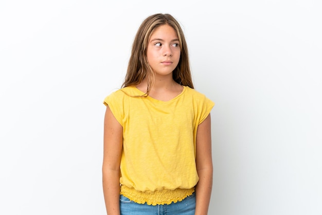 Little caucasian girl isolated on white background making doubts gesture looking side