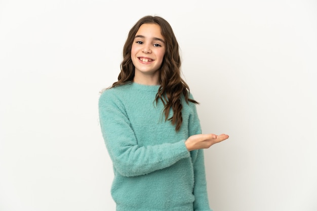 Little caucasian girl isolated on white background presenting an idea while looking smiling towards