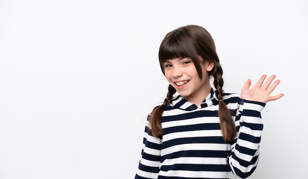 Little caucasian girl isolated on white background saluting with hand with happy expression