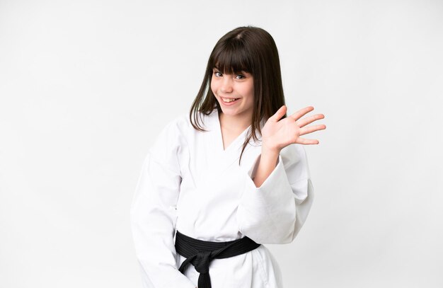 Photo little caucasian girl over isolated white background saluting with hand with happy expression