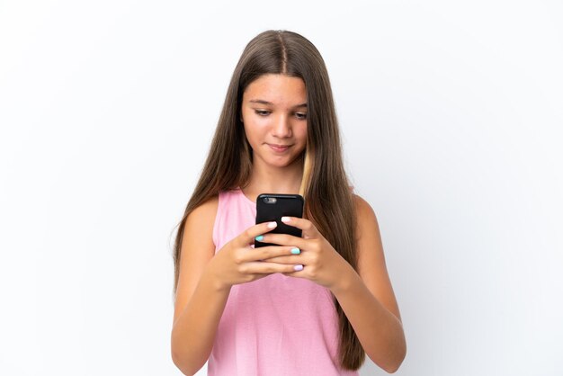 Little caucasian girl isolated on white background sending a message with the mobile