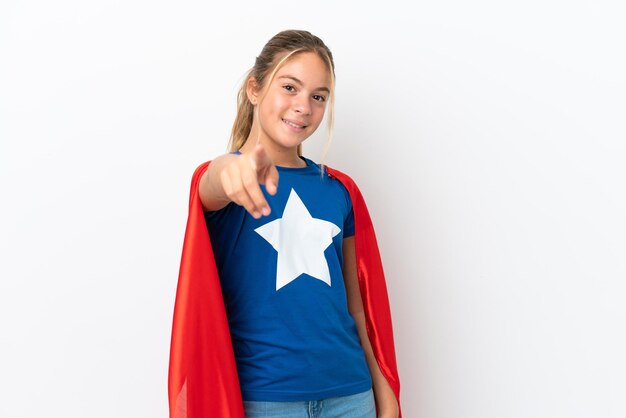 Little caucasian girl isolated on white background in superhero costume and pointing to the front