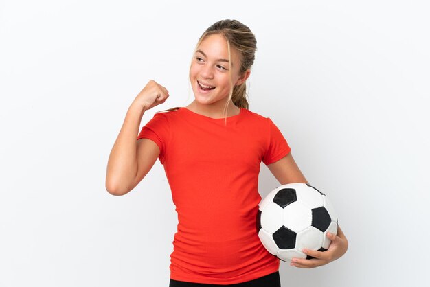 Piccola ragazza caucasica isolata su sfondo bianco con pallone da calcio che celebra una vittoria