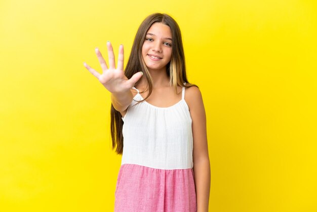 Little caucasian girl isolated on yellow background counting five with fingers