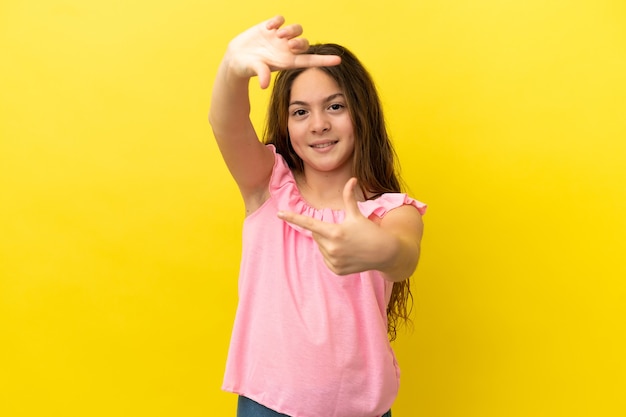 Little caucasian girl isolated on yellow background focusing face. Framing symbol