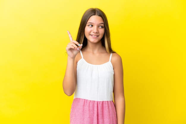 Little caucasian girl isolated on yellow background intending to realizes the solution while lifting a finger up