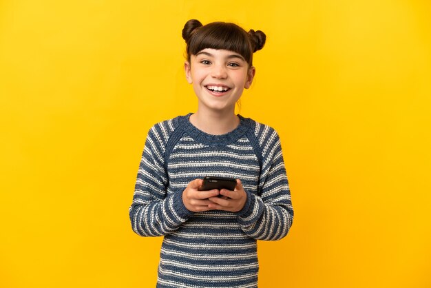 Little caucasian girl isolated on yellow surprised and sending a message