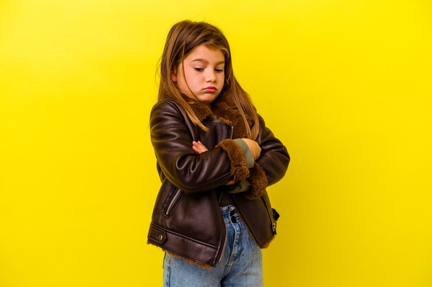 Little caucasian girl isolated on yellow tired of a repetitive task.