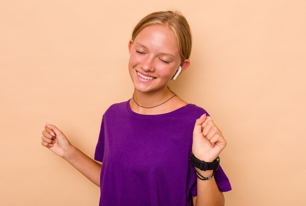 Little caucasian girl listening music isolated on beige background