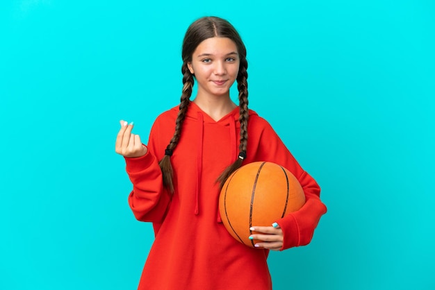 Photo little caucasian girl playing basketball isolated on blue background making money gesture