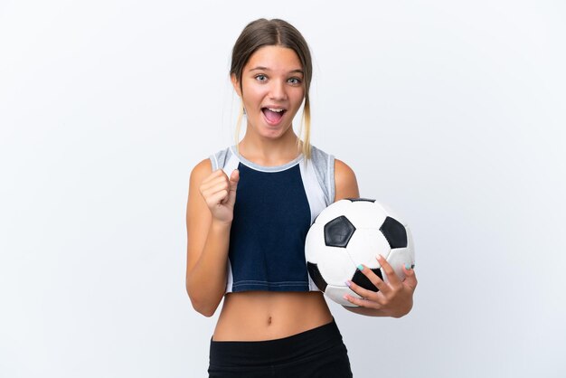 Piccola ragazza caucasica che gioca a calcio isolata su sfondo bianco che celebra una vittoria nella posizione del vincitore