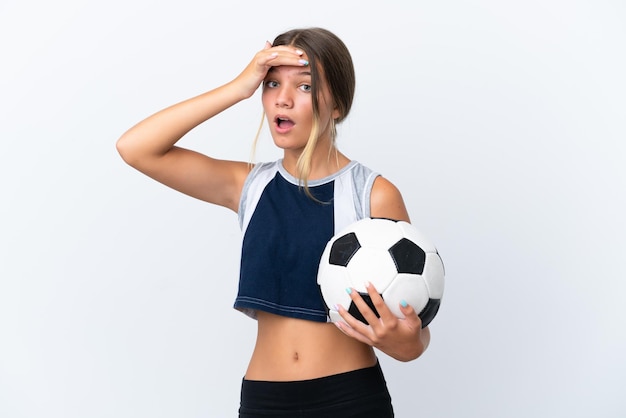 Foto piccola ragazza caucasica che gioca a calcio isolata su sfondo bianco facendo un gesto a sorpresa mentre guarda di lato