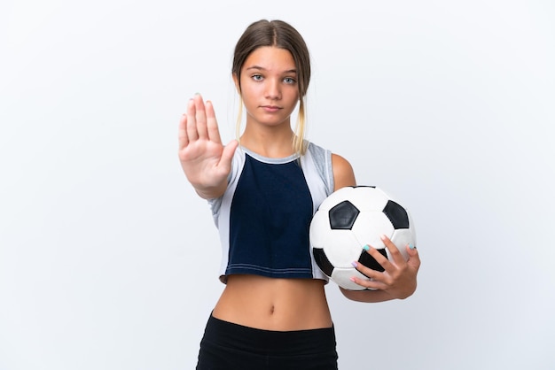 停止ジェスチャーを作る白い背景で隔離のサッカーをしている小さな白人の女の子