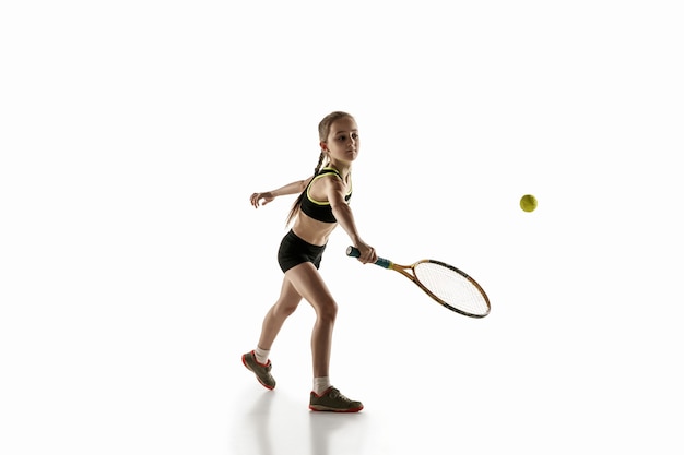 Little caucasian girl playing tennis isolated on white wall