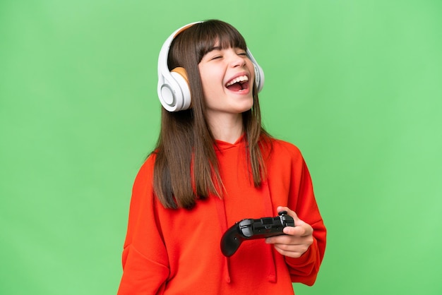 Little caucasian girl playing with a video game controller over isolated background laughing