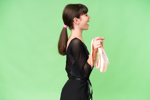 Little caucasian girl practicing ballet over isolated background laughing in lateral position