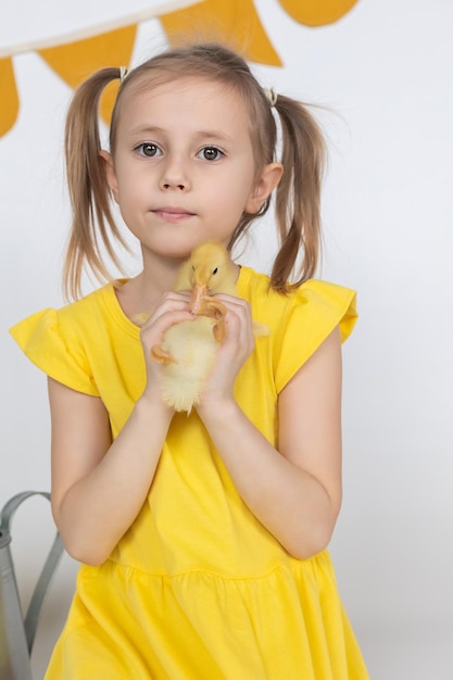 写真 手にかわいいアヒルの子を持っている小さな白人の女の子の就学前の年齢