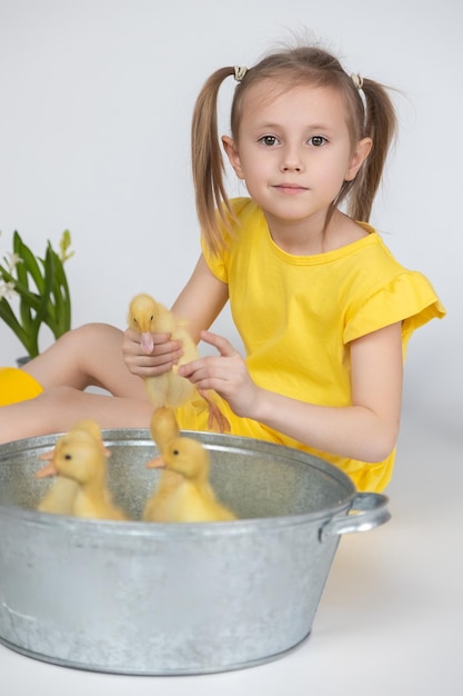 Little caucasian girl preschool age holding a cute duckling in the hands