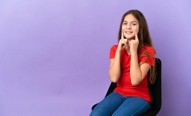 Piccola ragazza caucasica seduta su una sedia isolata su sfondo viola sorridente con un'espressione felice e piacevole