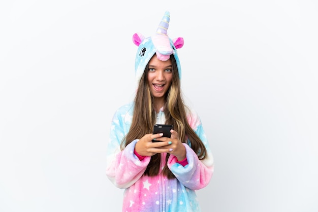 Little caucasian girl wearing unicorn pajama isolated on white background surprised and sending a message