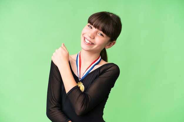 Little caucasian girl with medals over isolated background celebrating a victory