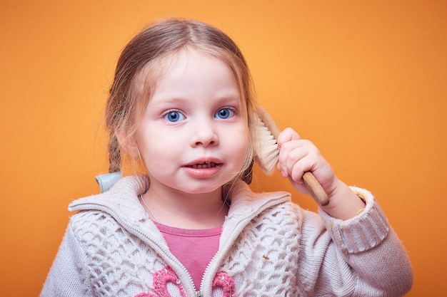 Piccola ragazza caucasica con un telefono in mano su un colorato