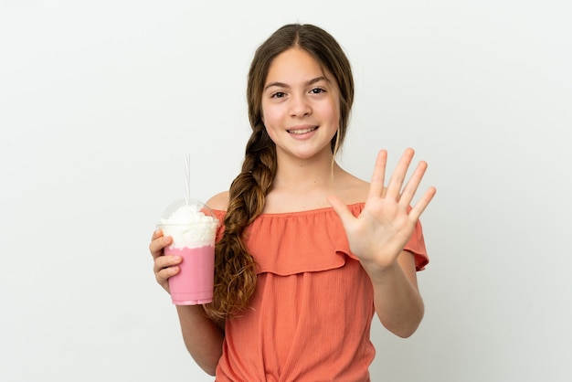 Little caucasian girl with strawberry milkshake isolated on white background counting five with fingers