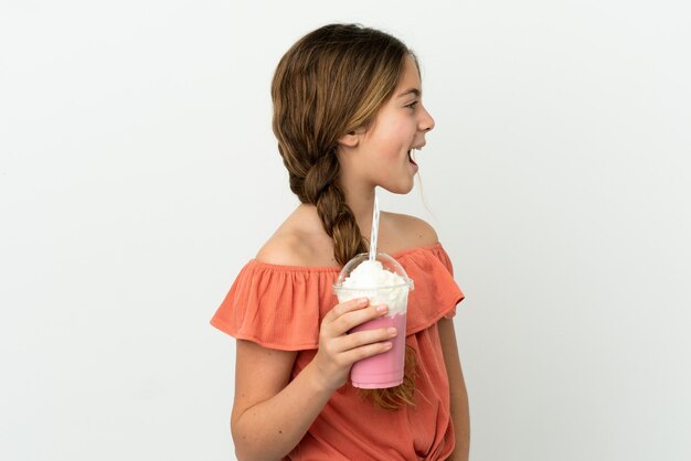 Little caucasian girl with strawberry milkshake isolated on white background laughing in lateral position