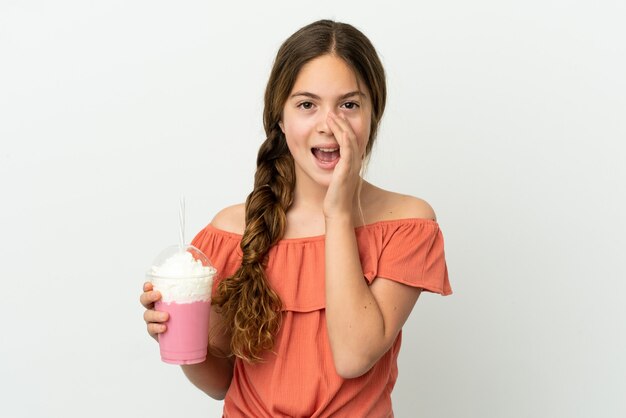 Маленькая кавказская девушка с клубничным молочным коктейлем на белом фоне кричит с широко открытым ртом
