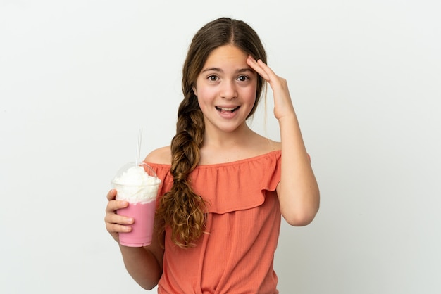 Little caucasian girl with strawberry milkshake isolated on white background with surprise expression